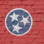 Tennessee flag displayed prominently on a textured brick wall, showcasing the state's colors and emblematic design.